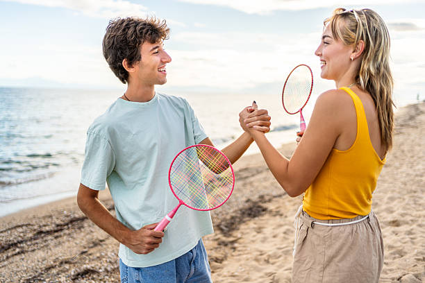 istock Young couple shaking hands after playing badminton on the beach 2215432821