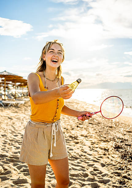 istock Young woman playing badminton on the beach at sunset 2215433116