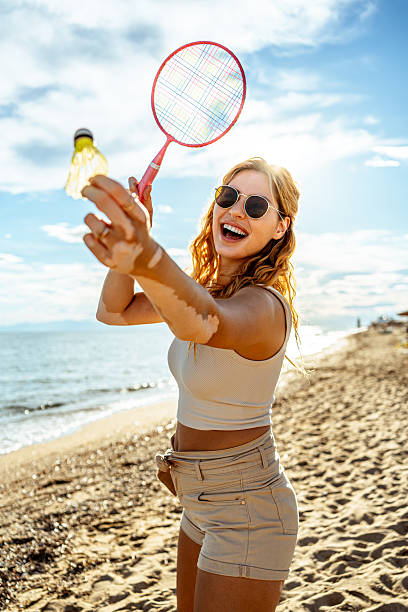 istock Young woman playing badminton on the beach 2215433192