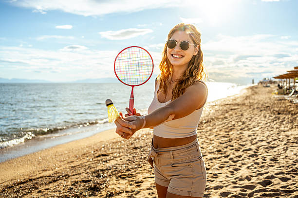 istock Young woman playing badminton on the beach at sunset 2215433509