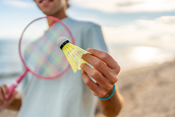 istock Young man holding shuttlecock on the beach getting ready to play badminton 2215433653