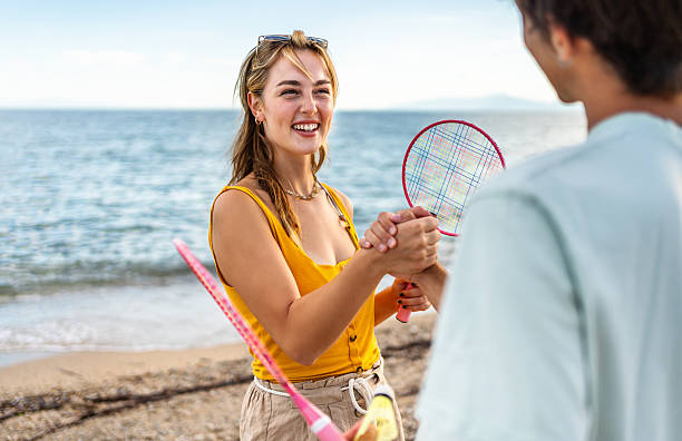 istock Happy couple shaking hands after playing beach badminton at sunset 2215433784