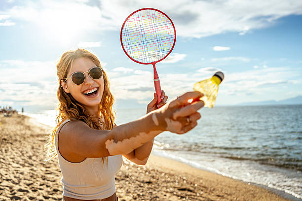 Young woman playing badminton on the beach