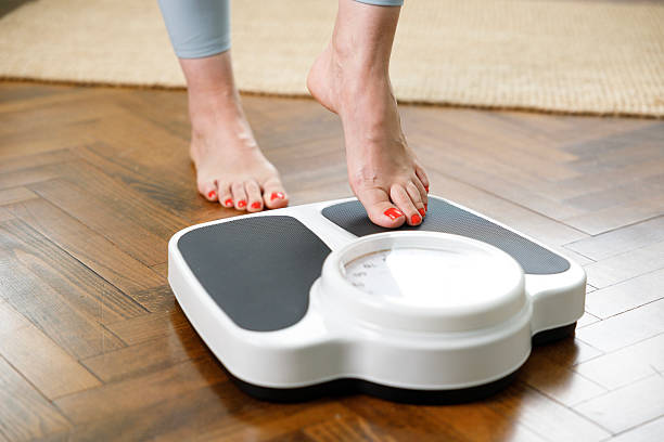 istock Woman checking weight on scale at home 2215434449