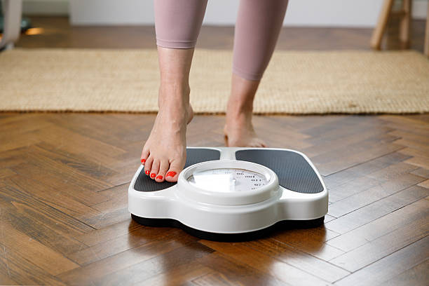 istock Woman checking weight on scale at home 2215434462