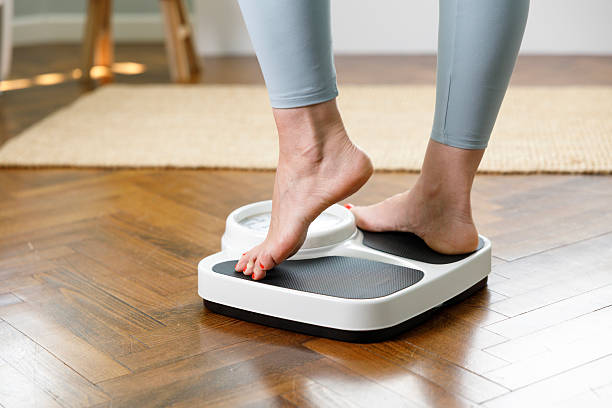 istock Woman checking weight on scale at home 2215434542