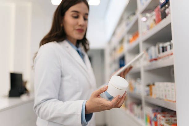 istock Pharmacist holding medicine jar and using digital tablet in pharmacy 2215435544