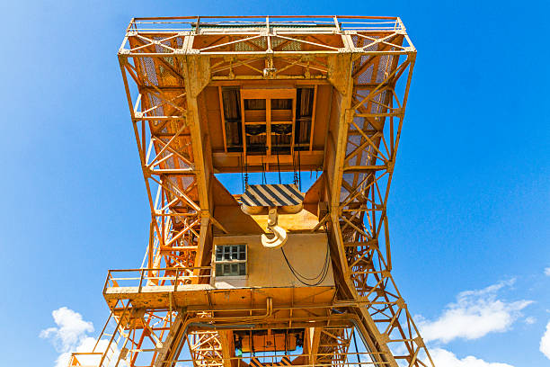 A powerful yellow industrial crane, shot from below, against a clear blue sky. The image emphasises heavy construction machinery, infrastructure and engineering. Ideal for illustrating topics related to industry, logistics, engineering and architectural development.