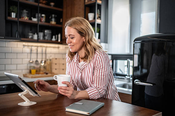 istock Woman enjoying morning coffee and browsing internet on tablet in kitchen 2215440815