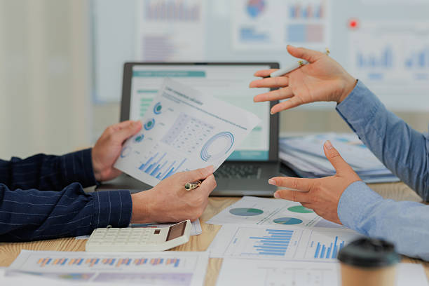 Corporate professionals in a strategy meeting analyzing charts and financial data, showcasing themes of business consulting, teamwork, and leadership development.