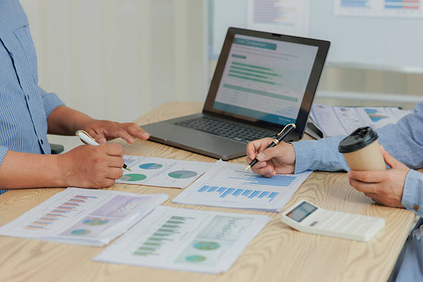 Corporate professionals in a strategy meeting analyzing charts and financial data, showcasing themes of business consulting, teamwork, and leadership development.