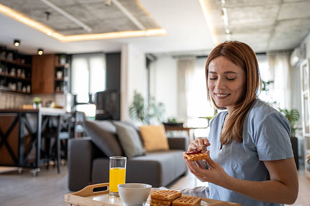 istock Smiling woman spreading jam on waffles for breakfast at home 2215445238