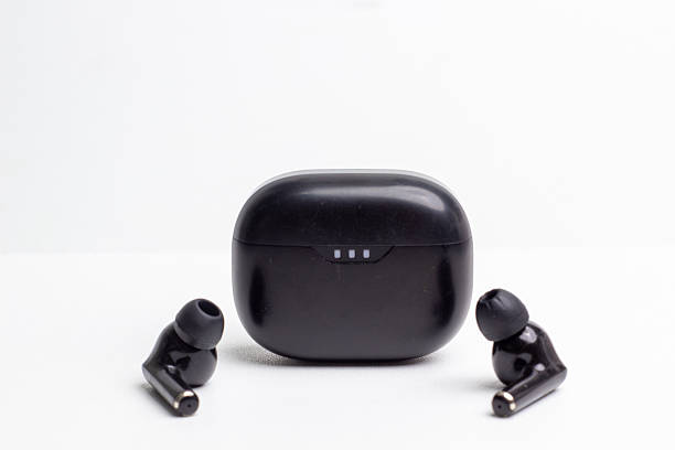 istock Glossy black wireless earbuds with charging case on white background. 2215445244