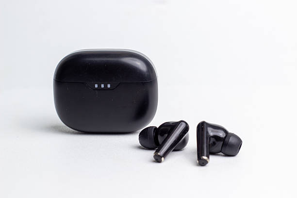 istock Glossy black wireless earbuds with charging case on white background. 2215445252