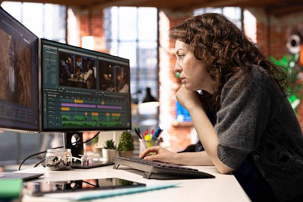 Focused editor woman works on video montage in a creative software Focused editor woman works on video montage in a creative software at agency office, digital media. Filmmaker using dual monitors to edit footage and create content, post production. female film editor stock pictures, royalty-free photos & images