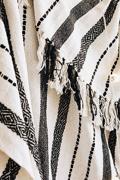 Handwoven textile featuring geometric patterns and fringed edges displayed in a cozy setting