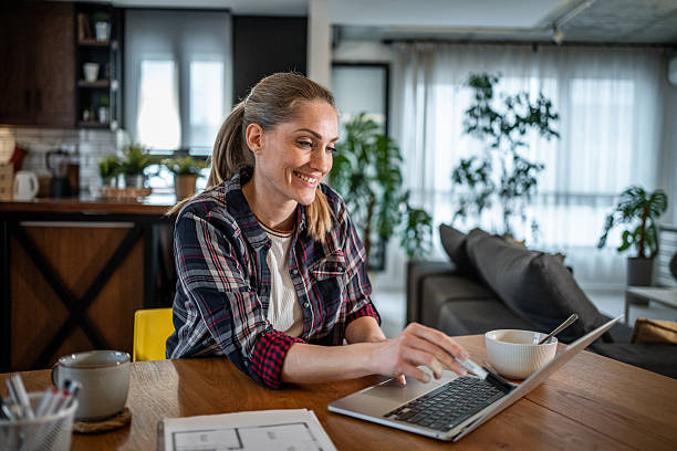 istock Smiling architect working from home on a laptop and reviewing plans 2215447028