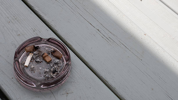 istock Dirty Ashtray with Cigarette Butts and Ashes on Wooden Surface 2215447082