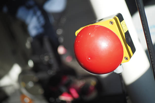 A large, bright red emergency button is prominently mounted on a post near a bustling city street. The surroundings include blurred figures and vehicles, implying urgency.