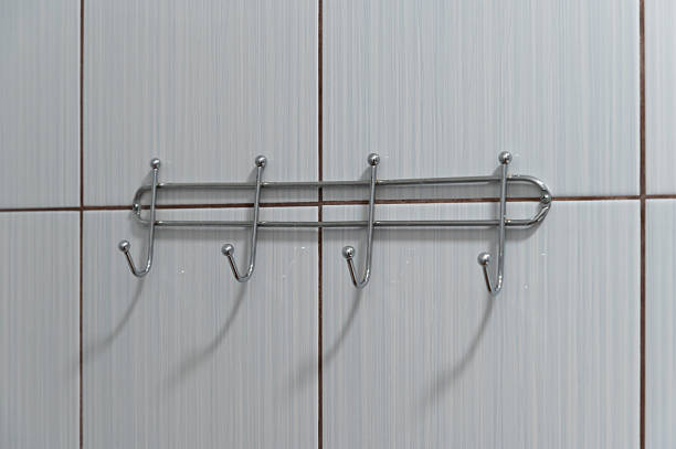 A close-up view of a chrome-plated towel hook rack mounted on a tiled bathroom wall. The simple and clean design adds a functional and modern touch to the interior.