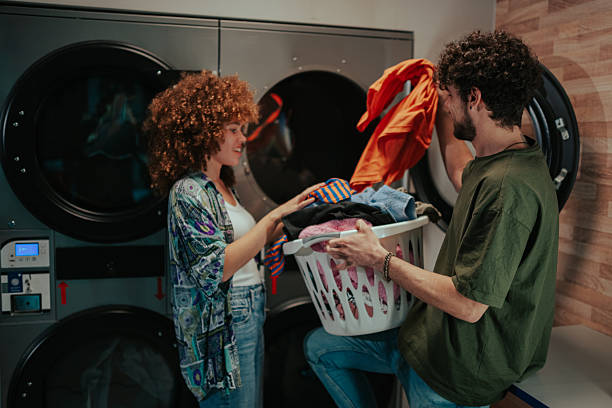 istock Young couple doing laundry at laundromat having fun 2215453535