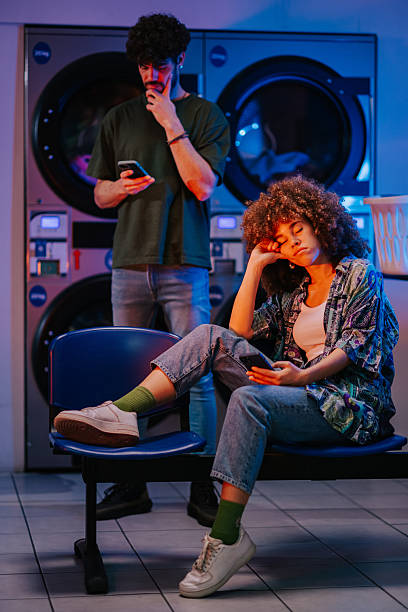 istock Young people waiting for laundry to finish at laundromat 2215453773