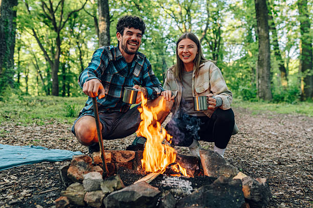 istock Hikers enjoying hot drinks by campfire in forest 2215455643