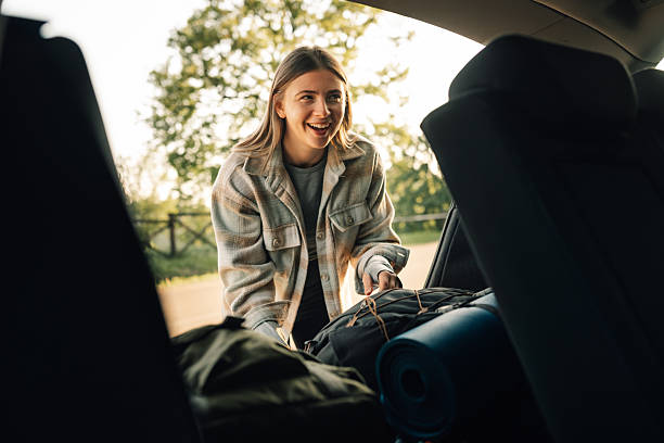 istock Young woman loading backpacks into car trunk for road trip 2215455644