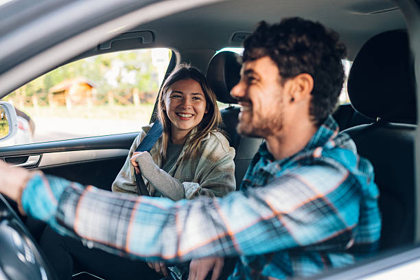 istock Young couple smiling and driving in car 2215455679