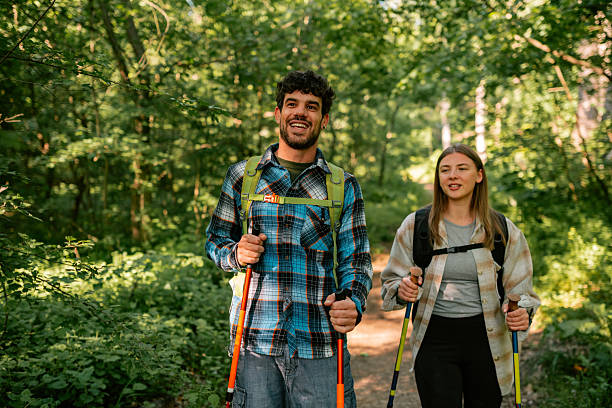 istock Hikers walking in forest using trekking poles 2215455710