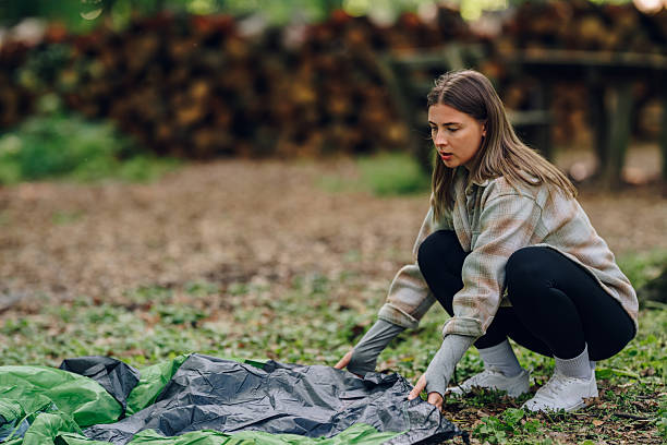 istock Young woman setting up tent in a forest campground 2215455782