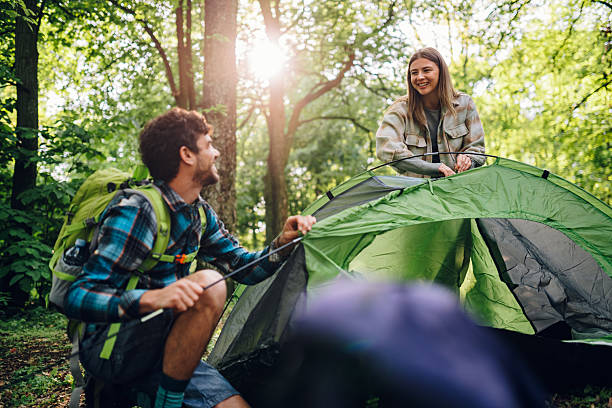 Hikers setting up tent in forest during camping trip