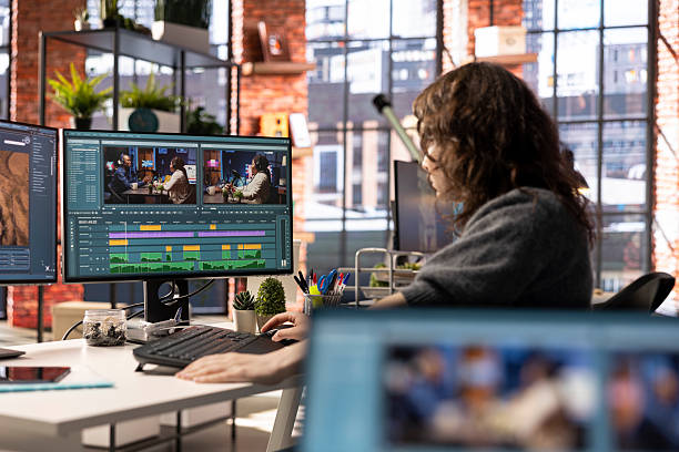 Young woman video editor working with dual monitors in creative agency Young woman video editor working with dual monitors in creative agency, editing video footage and does color grading for the creative process. Post production to create content. female film editor stock pictures, royalty-free photos & images