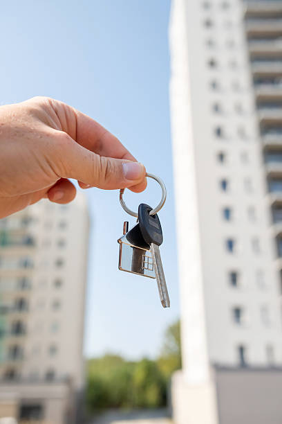 istock A person is standing while holding a set of keys in front of a tall building structure 2215465979