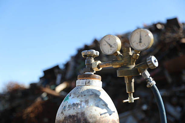 The image shows a pressurized oxygen cylinder with a mounted pressure regulator that has two pressure gauges. The gauges are used to measure the gas pressure — one shows the oxygen pressure inside the cylinder, while the other shows the working oxygen pressure coming out of the regulator.This type of equipment is commonly used in welding, medicine, and industry where precise oxygen dosing is important. The background of the image is blurry and indistinct, which further highlights the technical details in the foreground.