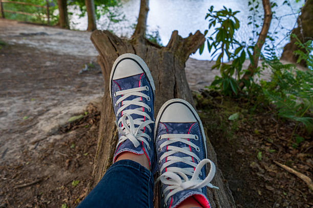 Sitting on a tree trunk. Blue sneakers on the feet.