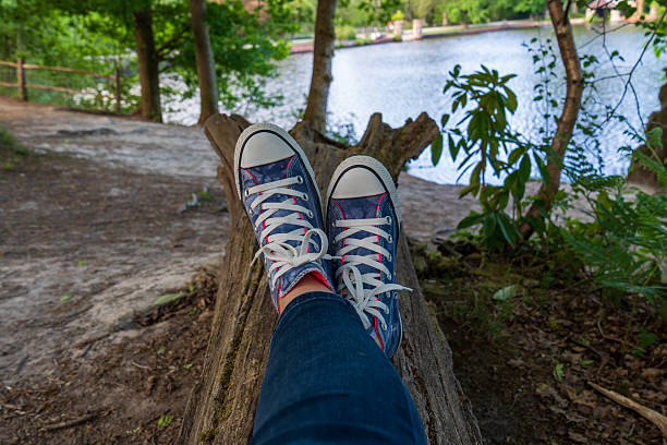 Sitting on a tree trunk. Blue sneakers on the feet.