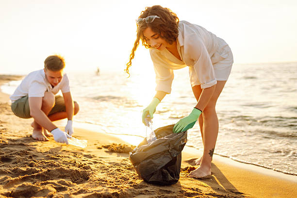istock Young friends actively participate in beach cleanup. 2215476928