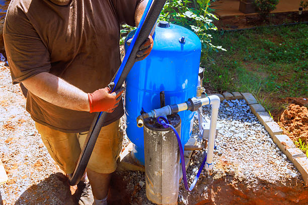 istock Worker installs water filtration system in backyard during sunny afternoon 2215477348