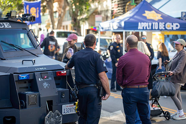 Police recruiting in San Luis Obispo Ca. at the Thursday farmers market on 05/15/25. There is a police SWAT vehicle  with some officers and civilians standing around.