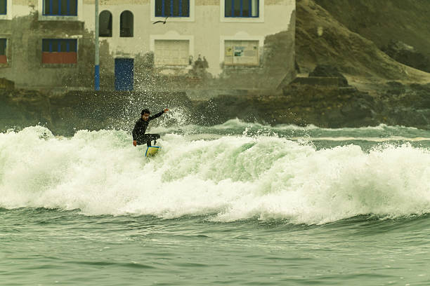 Surfer skillfully riding a wave close to the shore on a cloudy day, showcasing the thrill and excitement of ocean sports