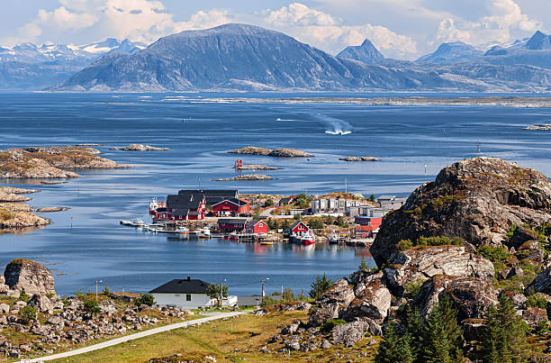 Picturesque village of Lovund nestled among rocky islets, with vibrant houses and dramatic mountain backdrop in Norway.