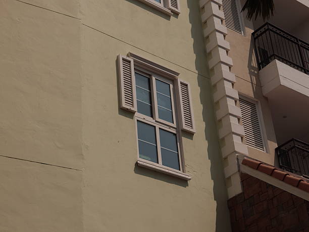 A contemporary modern building featuring a stylish shuttered window that stands out against a soft pastel wall