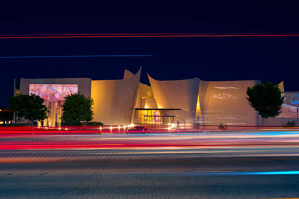 Puebla, Pue., Mexico - March 27, 2024: shot in the evening with rays from passing cars on the walls of entrance Museo Internacional del Barroco in the evening. the walls are illuminated with yellow lamps. the sky is dark - the road is concrete, the walls are made of tiles.