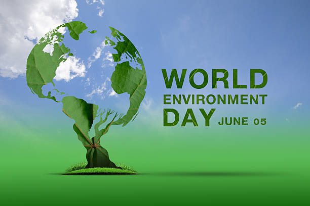 istock Creative illustration of a globe formed by green leaves, symbolizing World Environment Day on June 5, with a tree trunk and grass on a vibrant green background under a blue sky with clouds. 2215489421