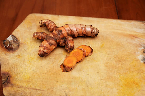 Fresh Turmeric root with slices on wooden cutting board, making health drinks, herb, ingredients