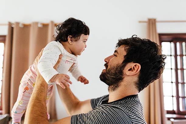 istock Father lifting baby in playful moment 2215496959