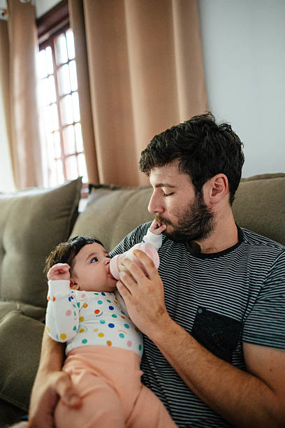 istock Father feeding baby with bottle on sofa 2215497022