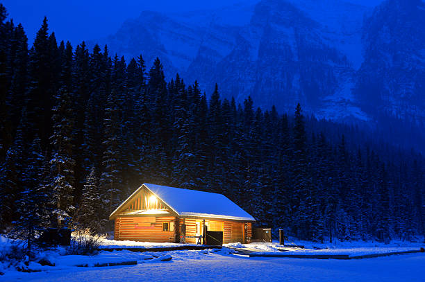 Fantastic winter landscape with wooden house in snowy mountains. Starry sky with Milky Way and snow covered hut. Christmas holiday and winter vacations concept