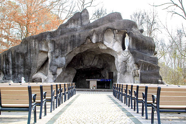 replica of the Lourdes Grotto, serving as an outdoor Catholic service area, likely featuring stone or rockwork mimicking the original grotto in France, and space for worshippers to gather for prayer and services.